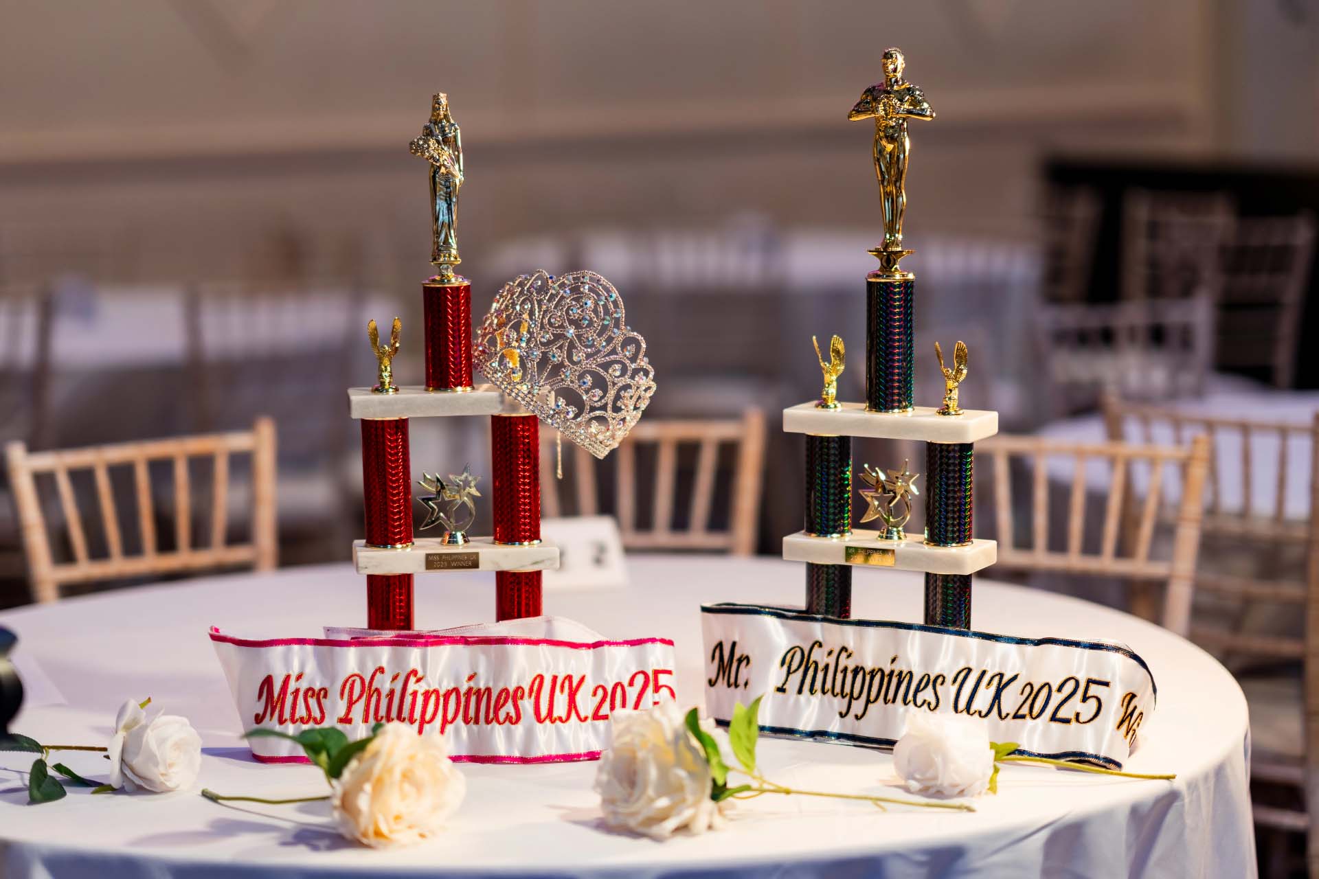 Miss and Mr. Philippines UK 2025 trophies with crowns displayed on a table.