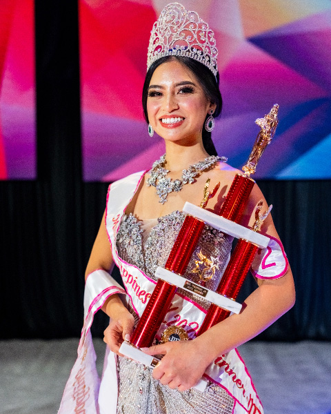 Miss Philippines UK 2025 holding her trophy and smiling at the event.